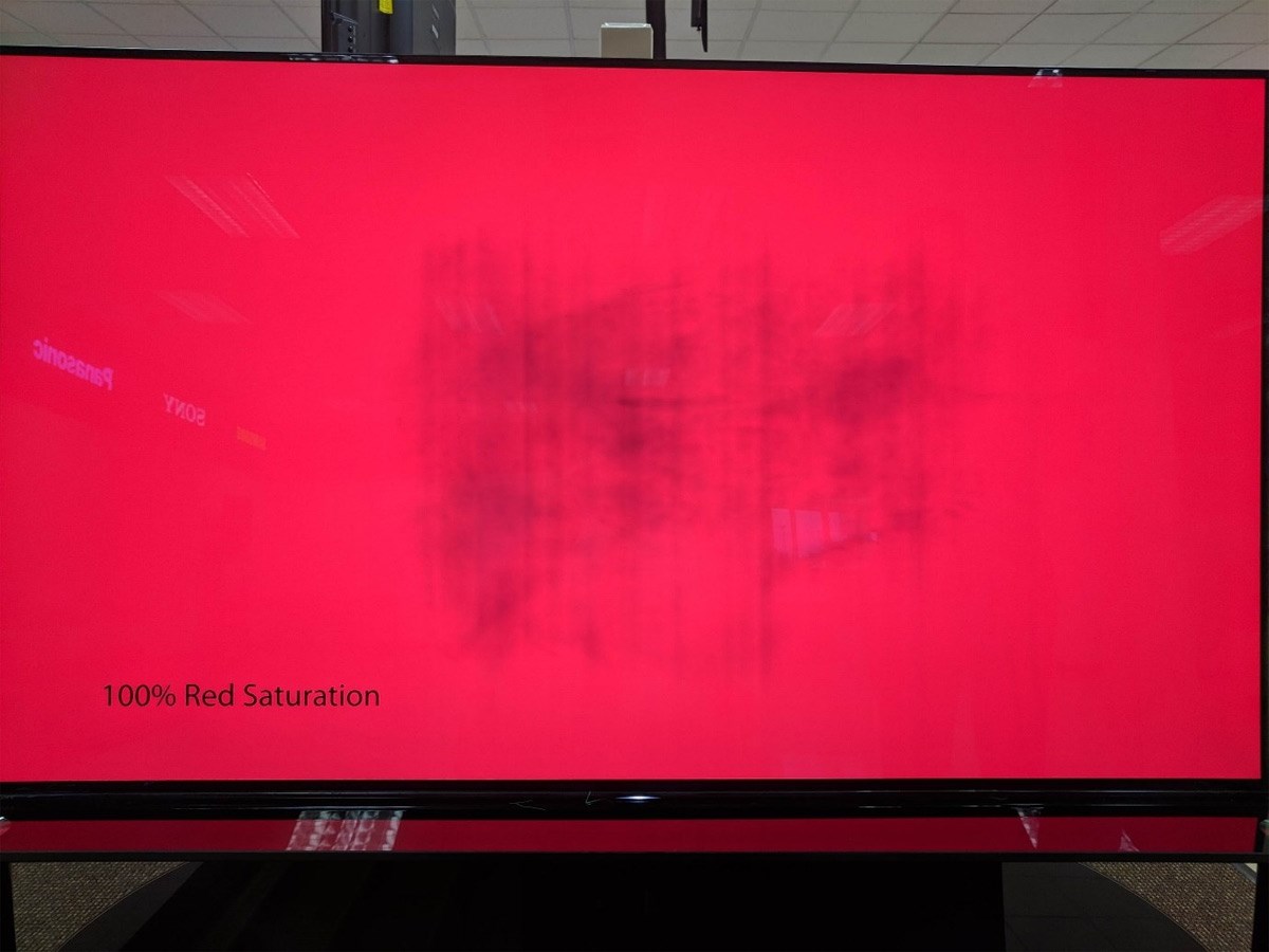 An OLED monitor with a red background showing a burn-in effect near the centre