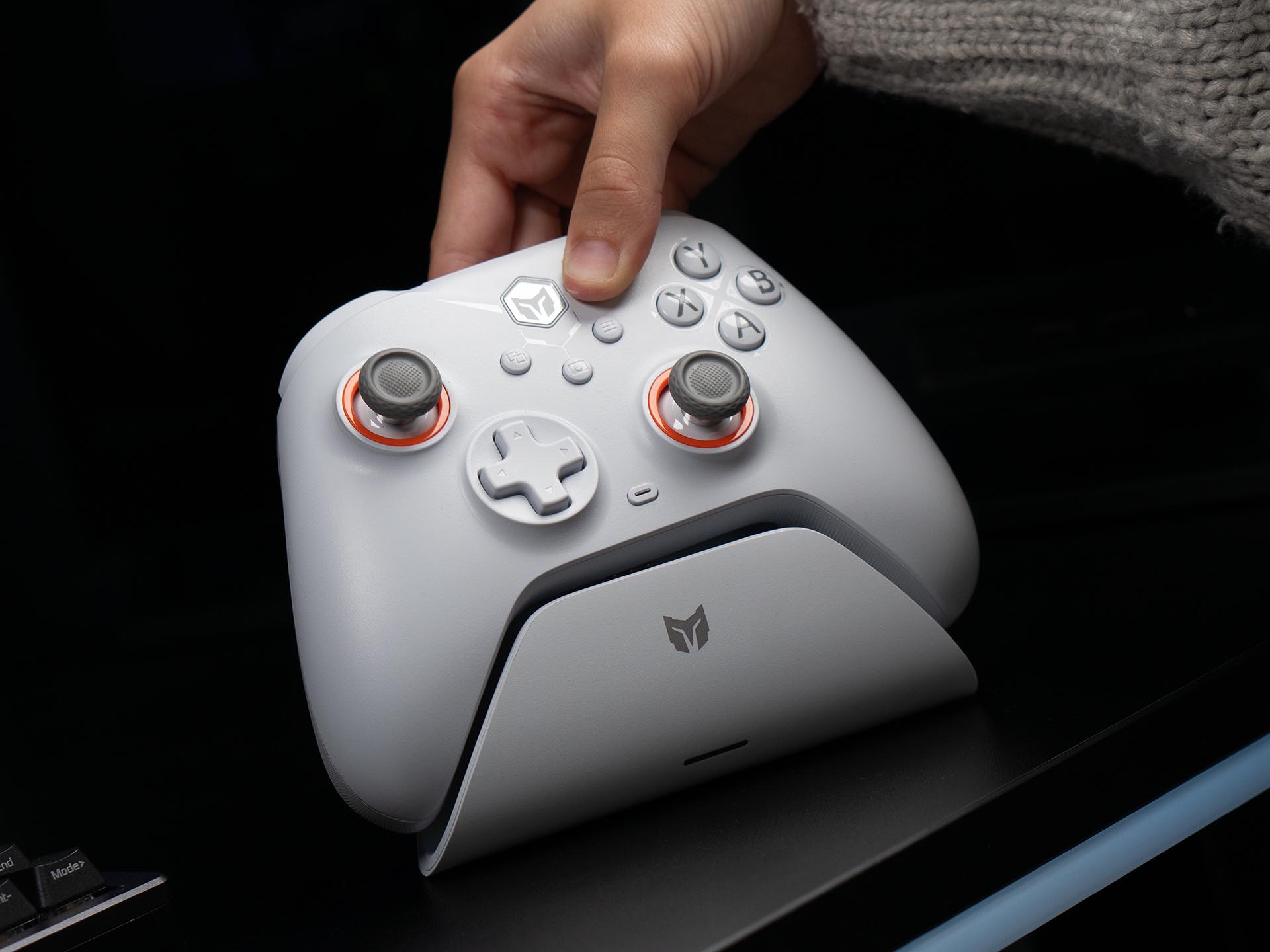 Hand placing a white BIGBIG WON Gale Hall wireless controller onto its matching charging dock on a gaming desk.