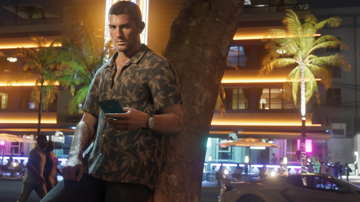 Jason Duval from GTA VI leans against a palm tree on a neon-lit street at night, wearing a tropical shirt and holding a phone, with palm trees and nightlife glowing in the background.