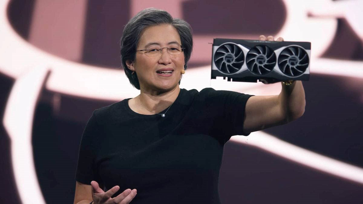 AMD CEO holding and showcasing a new Radeon graphics card during a presentation on stage, wearing a black shirt and speaking to the audience.