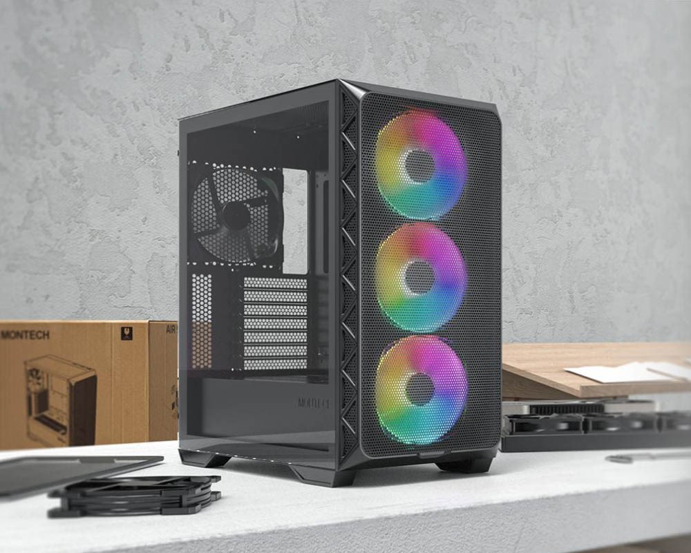 Montech Air 903 Max PC case featuring a mesh front panel with three vibrant ARGB fans and a tempered glass side panel, displayed on a workbench with PC components and packaging in the background.