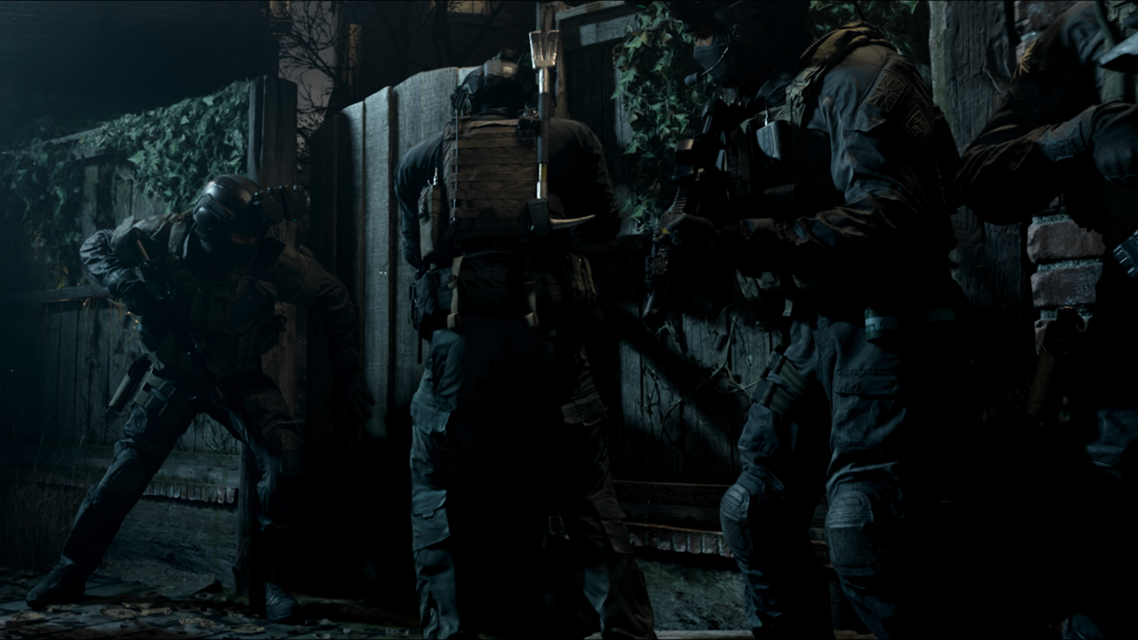 Scene from Call of Duty: Modern Warfare II showing a group of tactical soldiers preparing to breach a wooden gate under the cover of darkness, highlighting intense and realistic combat scenarios.