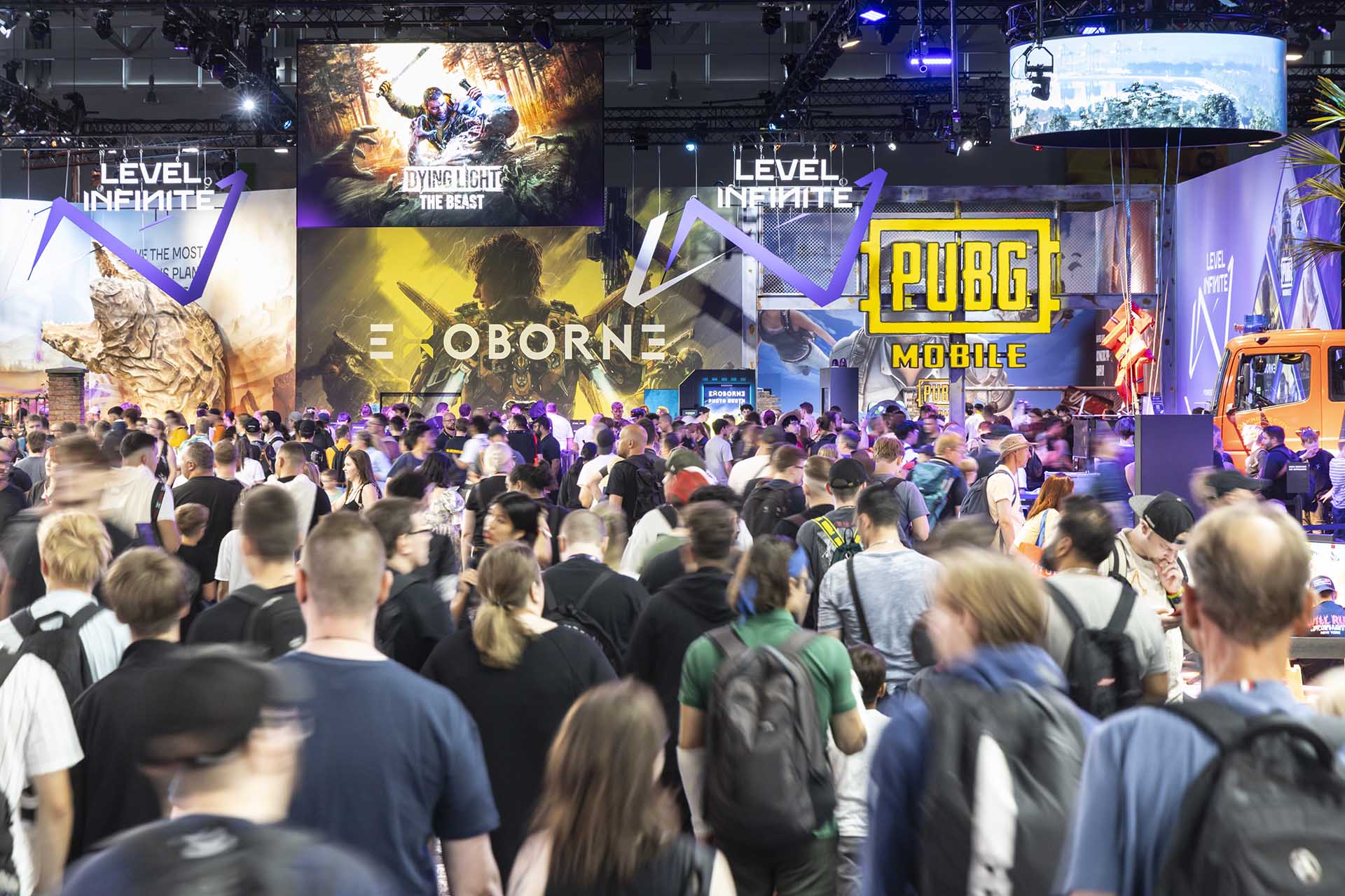 Crowds of gamers exploring booths at Gamescom 2025, featuring displays for PUBG Mobile, Dying Light: The Beast, and other major titles.