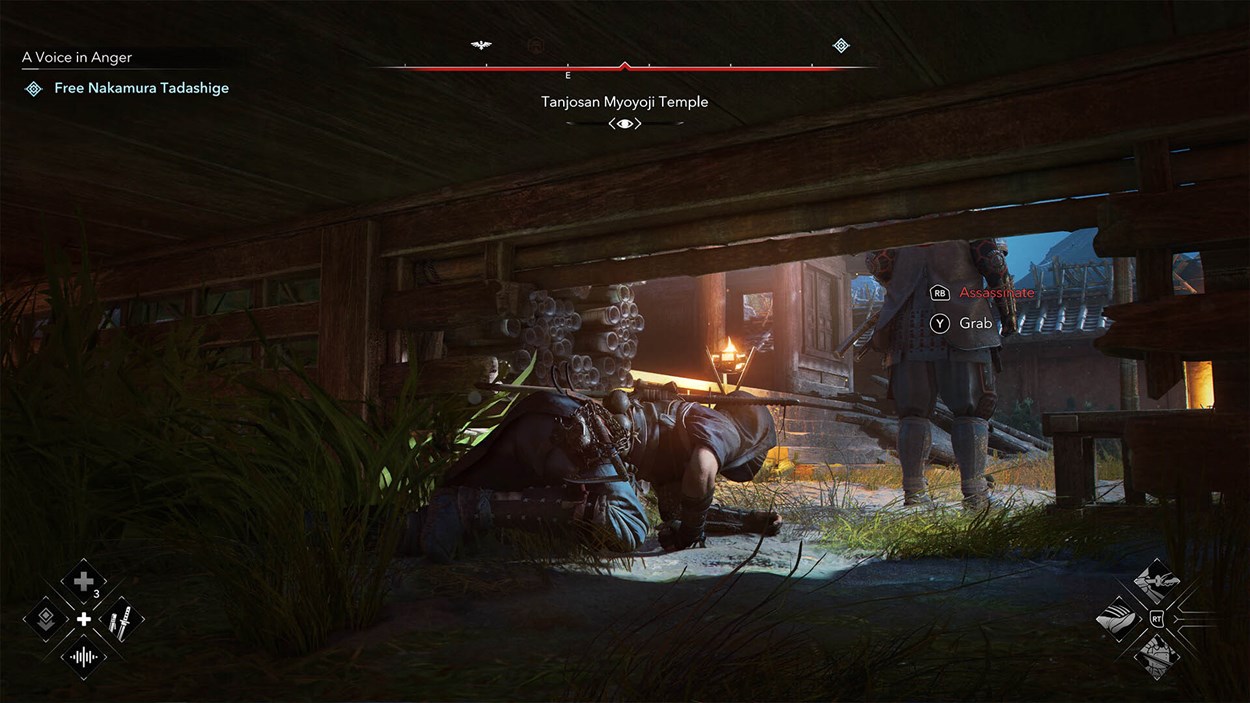 A stealth gameplay scene from Assassin’s Creed Shadows. The protagonist, a shinobi assassin, is crouched under a wooden structure, hidden in tall grass, preparing to strike. A heavily armored samurai guard stands unaware near a torch-lit entrance. The on-screen interface displays options to 'Assassinate' (RB button) or 'Grab' (Y button). The mission objective, 'Free Nakamura Tadashige,' is displayed in the top left, while the location, 'Tanjozan Myoyoji Temple,' appears at the top center. The environment is richly detailed with warm lighting, wooden architecture, and immersive shadows.