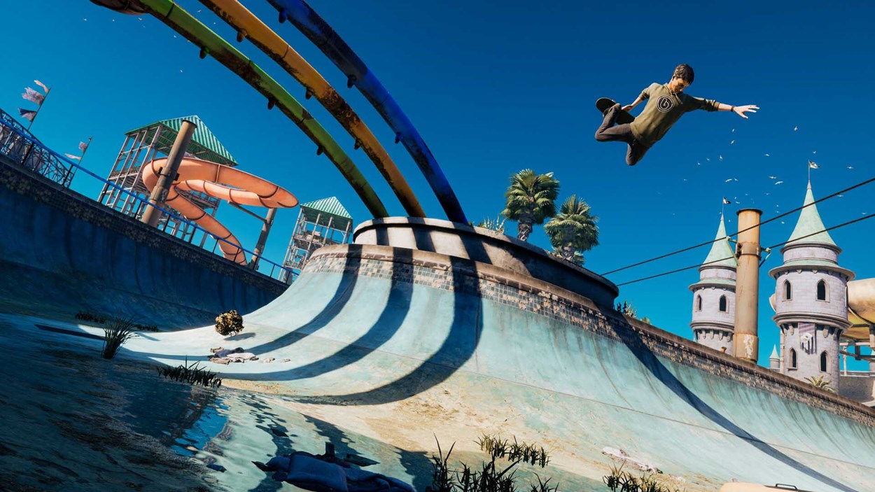 Skater launching into the air over an abandoned waterpark-themed halfpipe, with colourful slides and castle towers in the background.