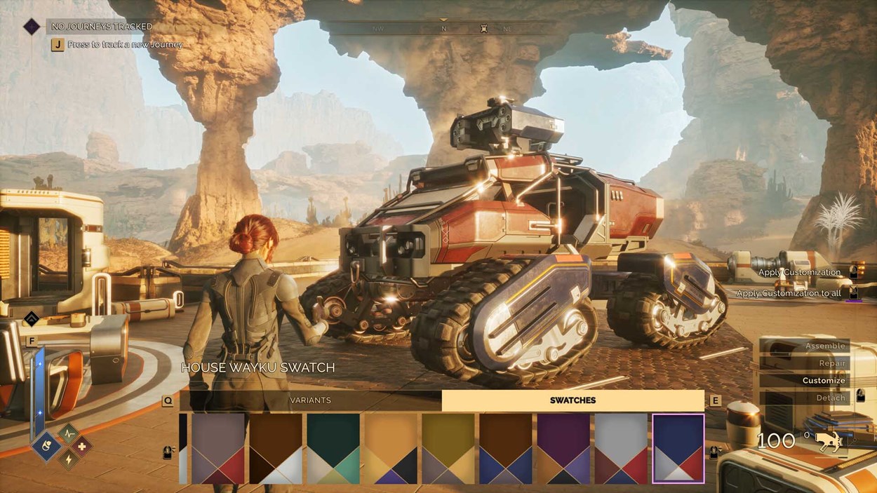 Player character in sci-fi gear customizes a heavily armored tracked vehicle in a desert outpost, with paint swatches and UI customization options visible on screen.